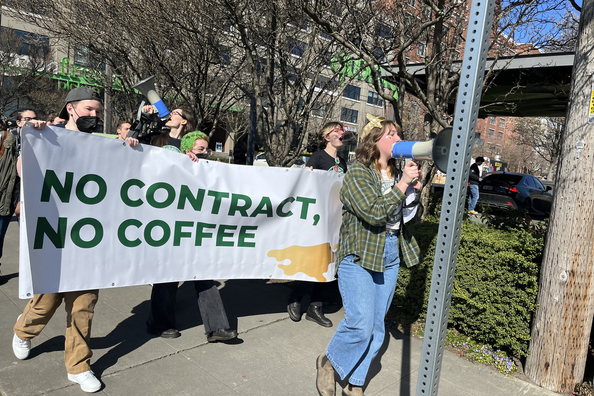 Protesters hold a banner reading “No contract, no coffee”