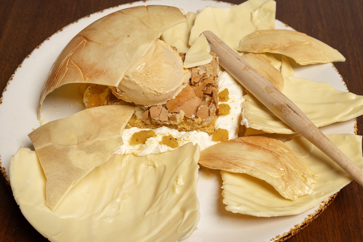 A smashed yellow meringue shell contains a scoop of ice cream.