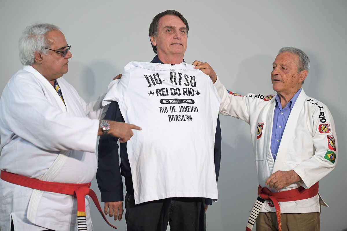 Brazilian President Jair Bolsonaro (center) receiving an honorary blackbelt from Robson Gracie (right) in 2018.