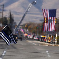 Stesha Bowden holds a flag as a procession of police vehicles moves along 4100 South en route to the interment of West Valley police officer Cody Brotherson in West Valley City on Monday, Nov. 14, 2016.