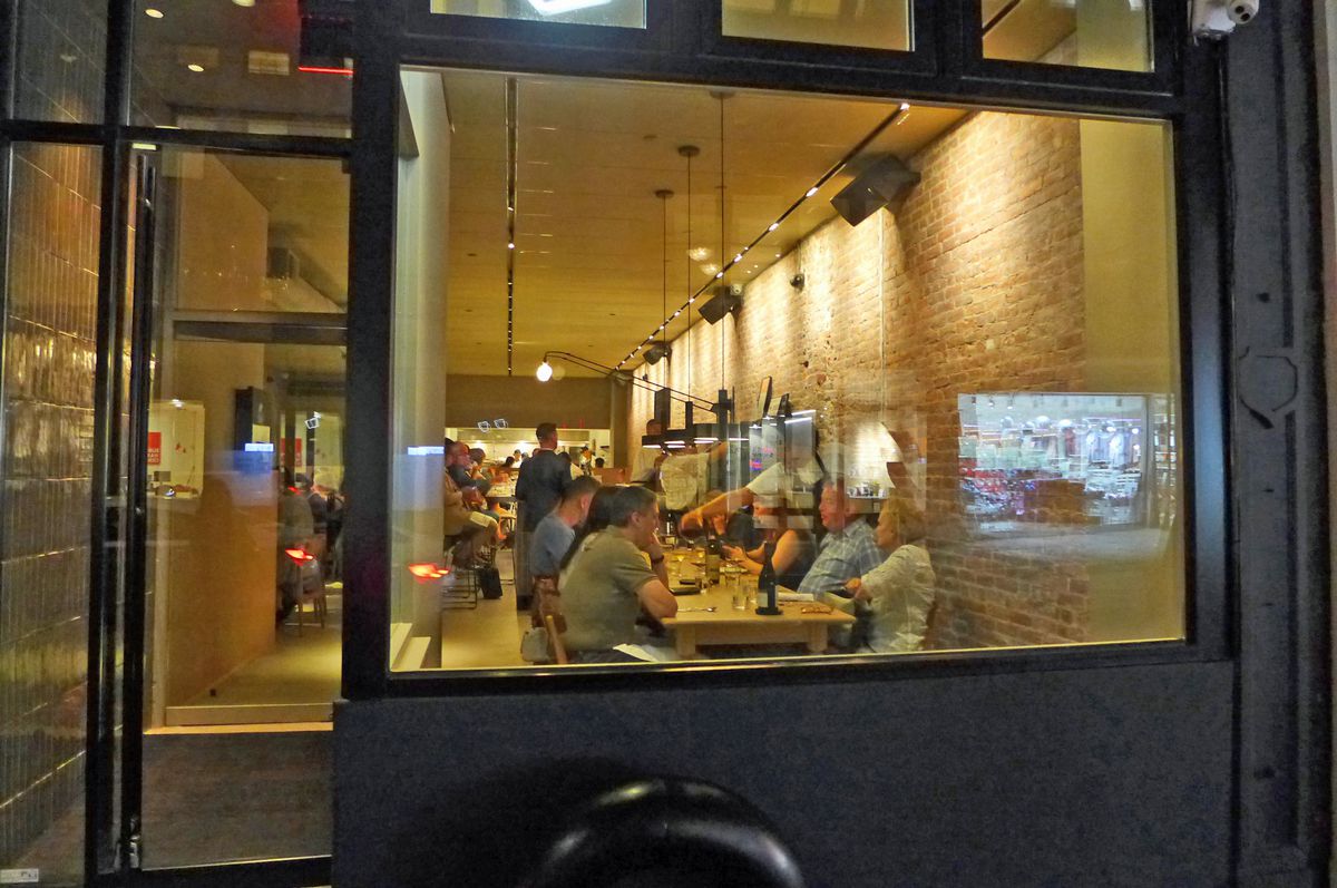 A table of diners is imperfectly seen through a window.