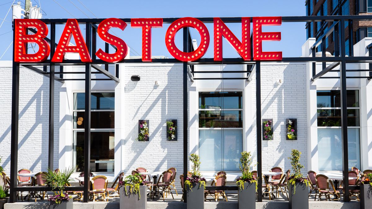 The bright whitewashed exterior and cafe style patio is in stark contract to the bright red neon Bastone Italian restaruant sign and blue skies in Atlanta. 