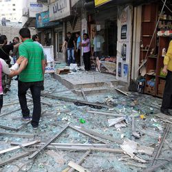 In this photo released by the Syrian official news agency SANA, Syrians walk on shattered glass from damaged shops at the scene of a powerful explosion which occurred in the central district of Marjeh, Damascus, Syria, Tuesday April 30, 2013. A powerful explosion rocked Damascus on Tuesday, causing scores of casualties, a day after the country's prime minister narrowly escaped an assassination attempt in the heart of the heavily protected capital. 