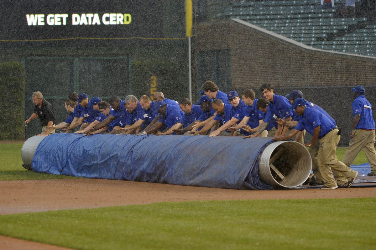 The grounds crew rolls out the tarp during the Chicago Cubs and Colorado Rockies game at Wrigley Field in Chicago, Illinois. The Cubs defeated the Rockies 5-0 in a rain-shortened eight inning game.  (Photo by Brian Kersey/Getty Images)