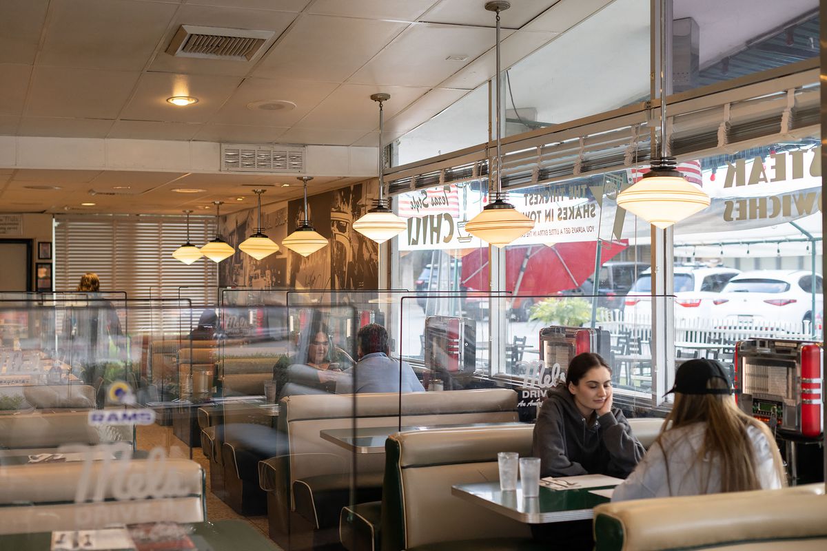Customers sit at booths between tall panes of glass inside a diner.