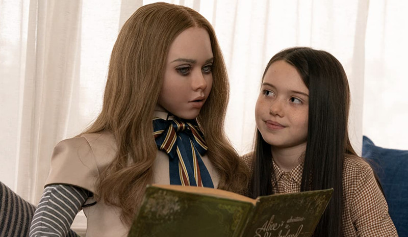 A still from the film showing the eerily life-like doll reading to Cady.