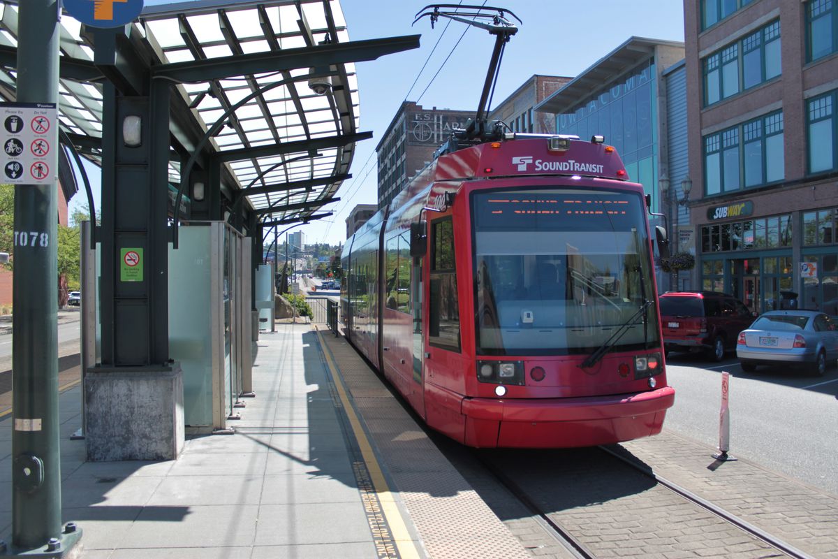 A red light rail car stopped at a station