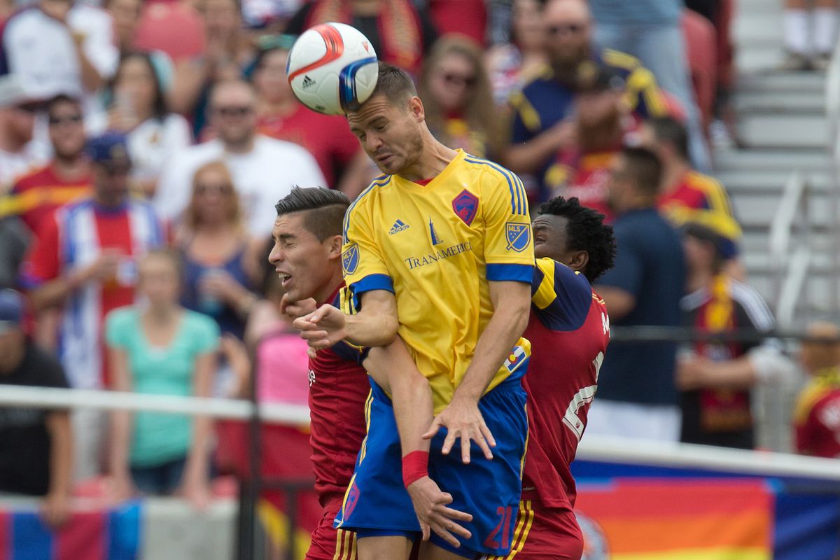 Luis Solignac going up between two RSL defenders and winning control of the ball.