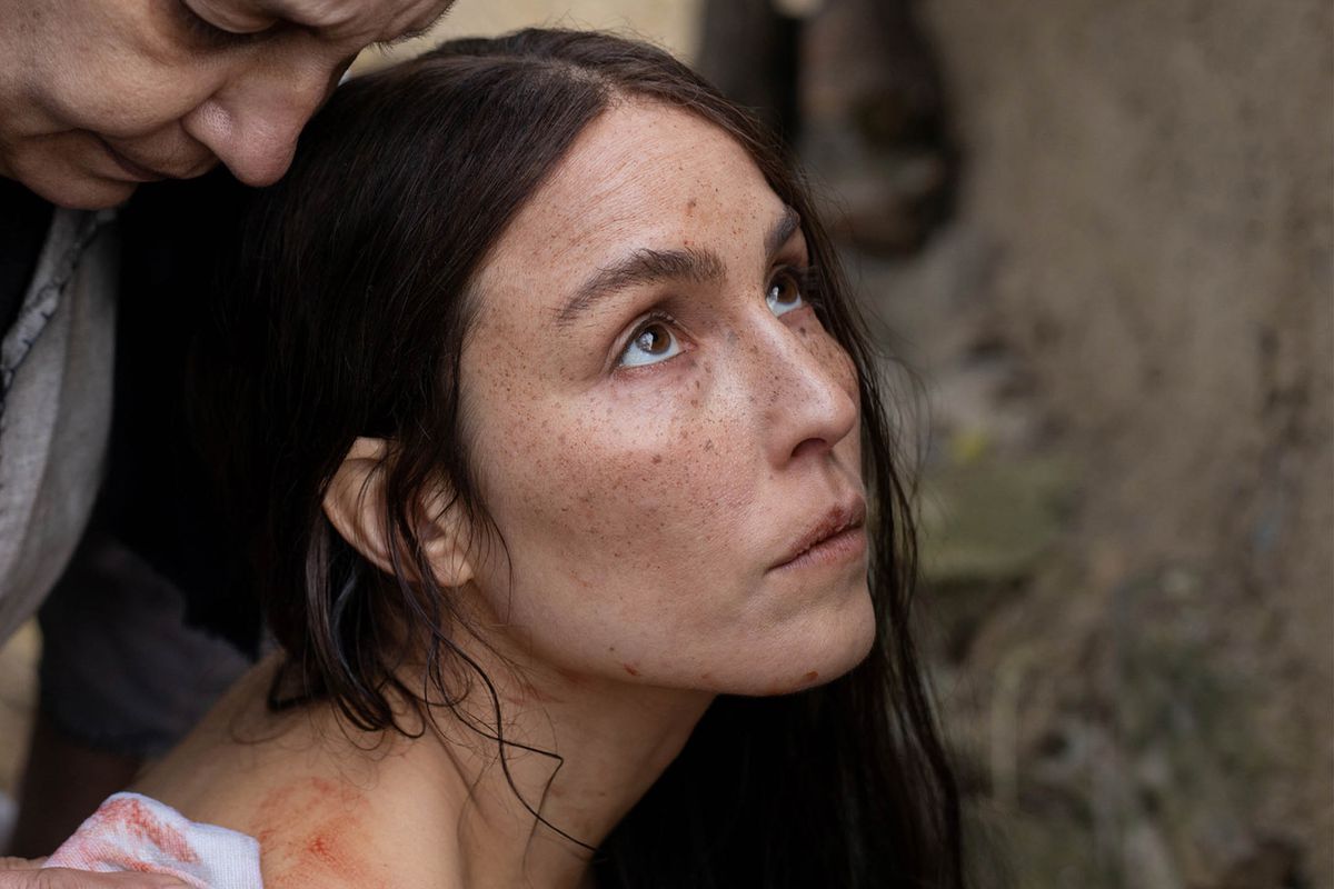 Noomi Rapace in closeup, blood on her shoulder and someone barely visible leaning over her, in&nbsp;You Won’t Be Alone