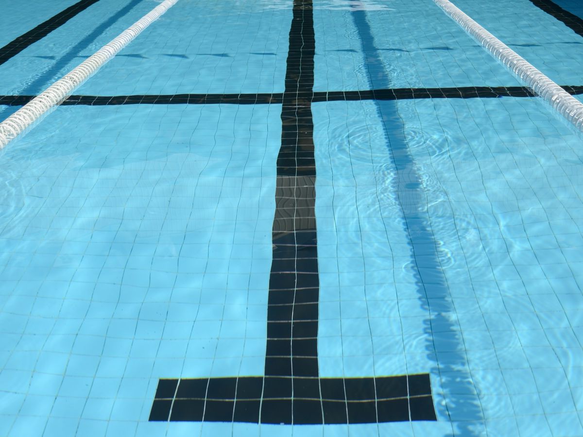 An outdoor pool lane with a t-shaped marking and two white lane dividers 