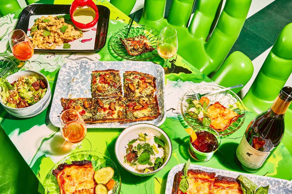 A lime green table laid out with pizzas and other food.