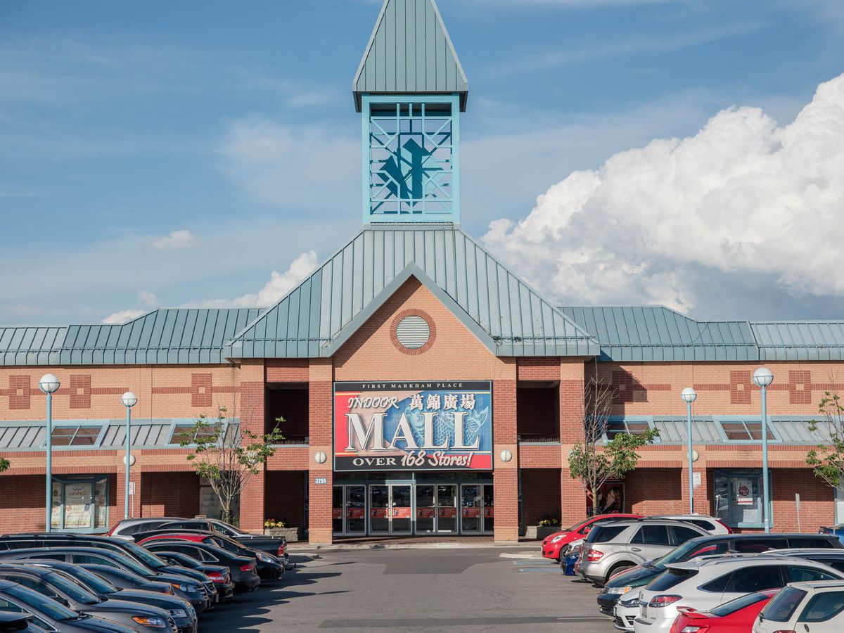 A mall exterior with large sign and a bell tower against a blue sky