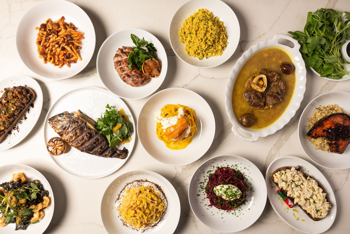 A full overhead shot of dishes, including pastas and fried fish, at a new Italian restaurant.