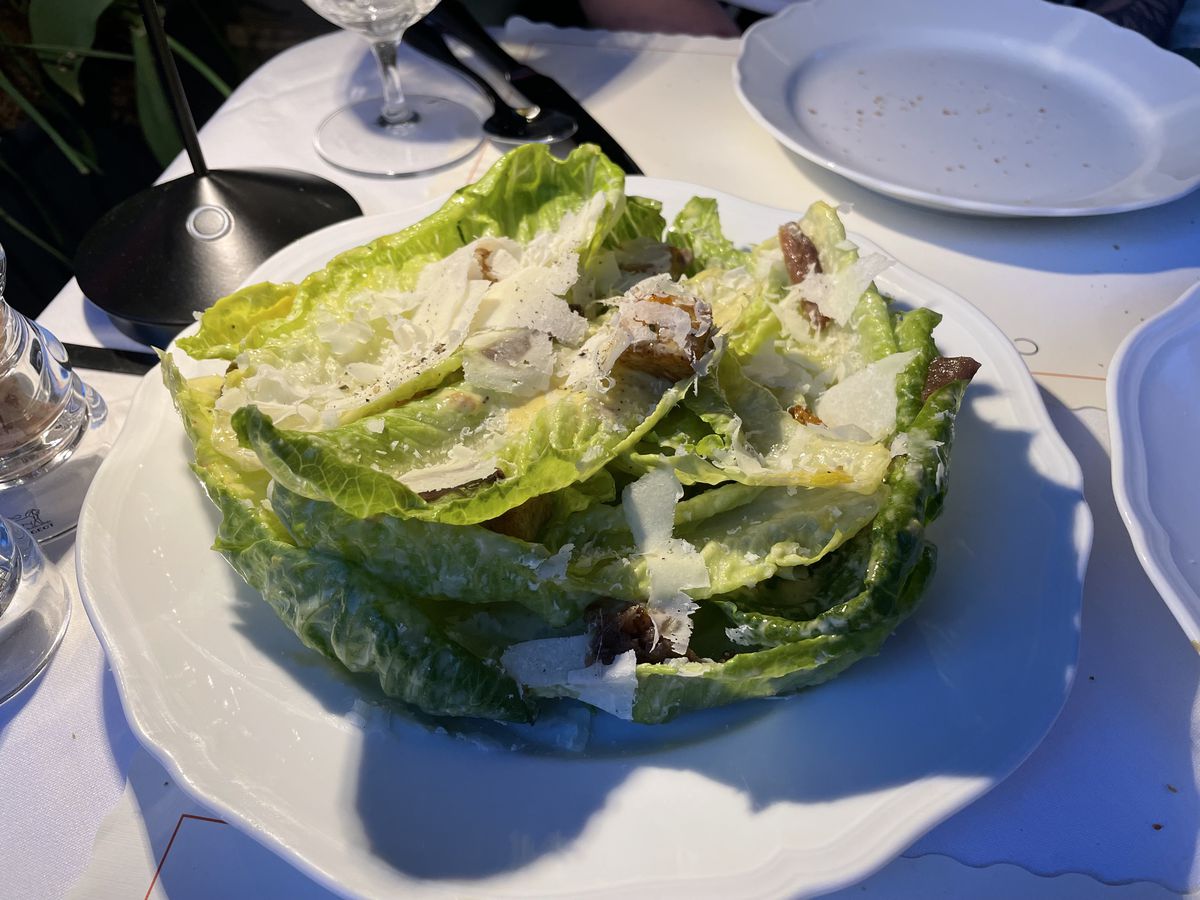 A Caesar salad with generous amounts of cheese and anchovy.