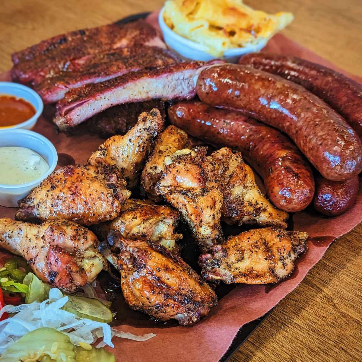 Platter of smoked ribs, sausage links, and smoked chicken wings. 