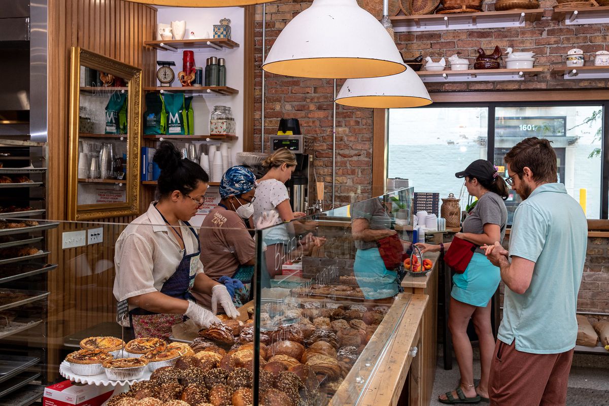 A bakery counter with customers on one side and workers on the other.