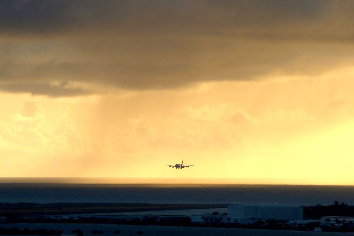 A plane lands as the sun sets over the international airport in Honolulu.