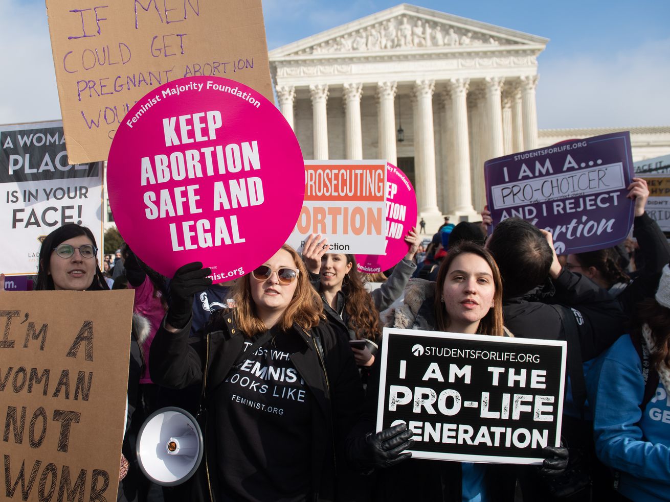 People at a rally outside the Supreme Court building carry signs that read “Keep abortion safe and legal” as well as “I am the pro-life generation.”