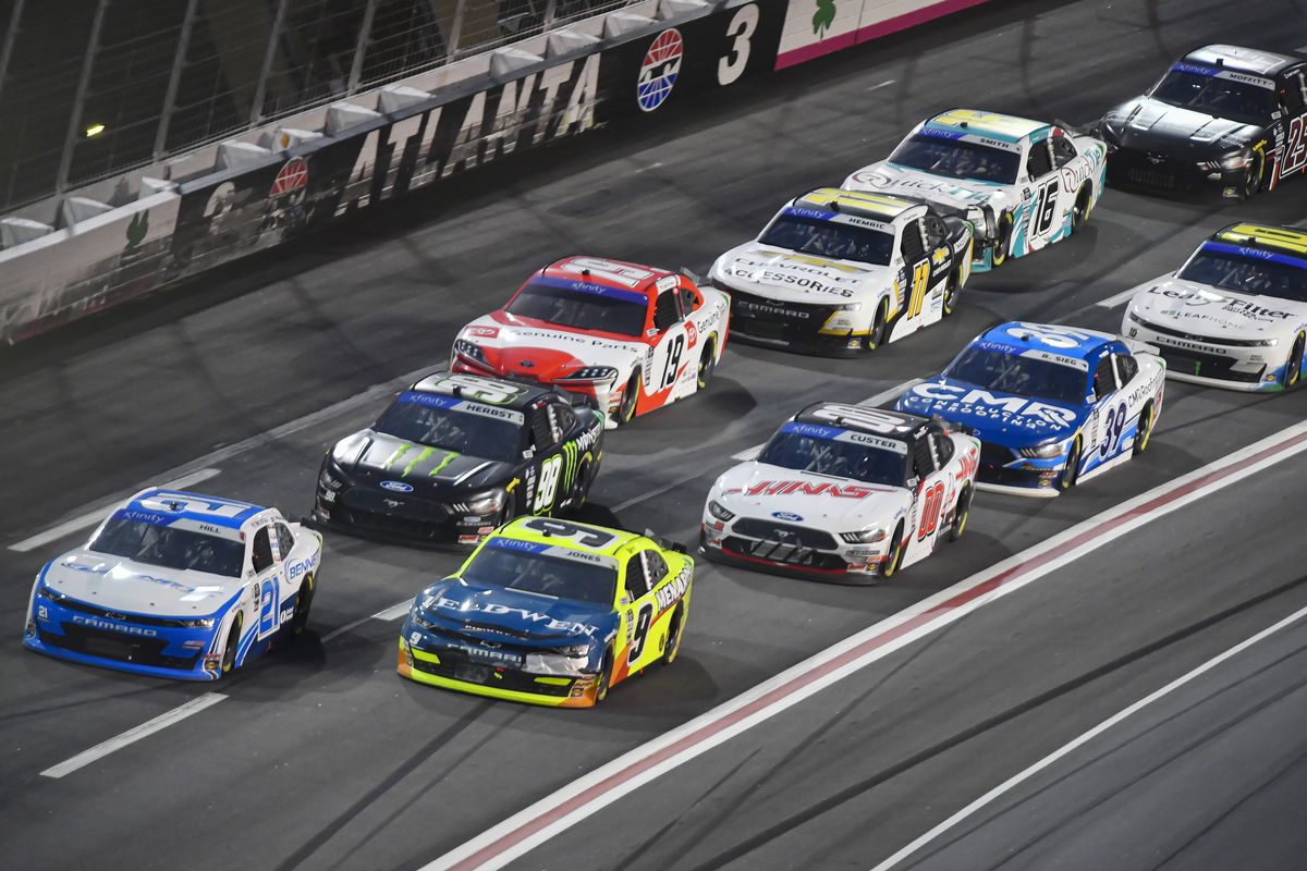 Austin Hill of the Bennett Transportation Chevrolet (21) and Brandon Jones of the Menards/Jeld-Wen Windows Chevrolet (9) lead a pack of cars into turn three during the RAPTOR King of Tough 250 in the NASCAR Xfinity Series on Saturday, March 18, 2023 at Atlanta Motor Speedway in Hampton, GA.