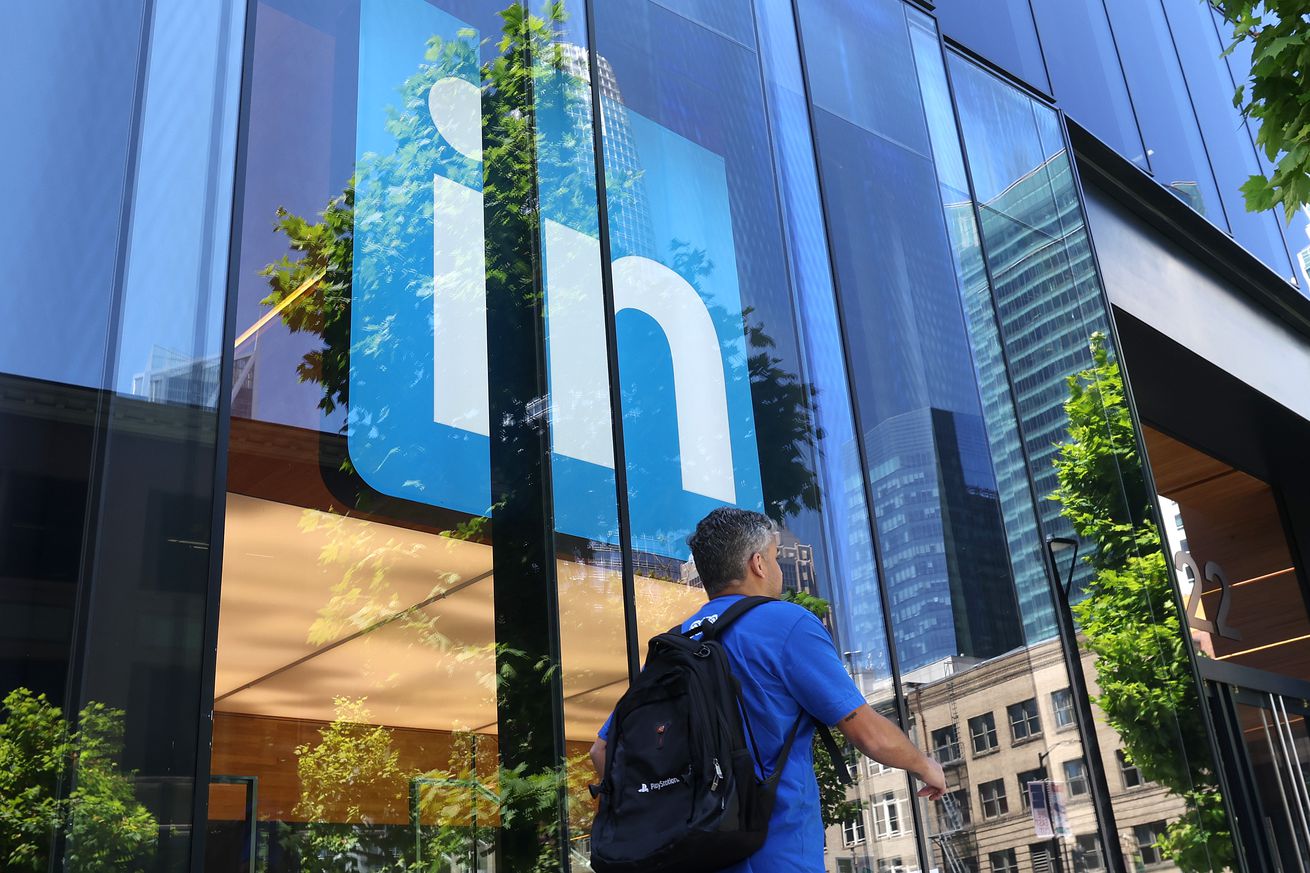 Someone walks past the LinkedIn office logo.
