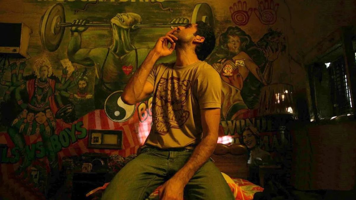 Dev (Abhay Deol) smoking a cigarette in a room filled with graffiti in Dev.D.