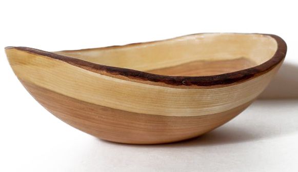 An elegant wooden bowl, made of cherry wood in light, medium, and dark tones, sits on a white background