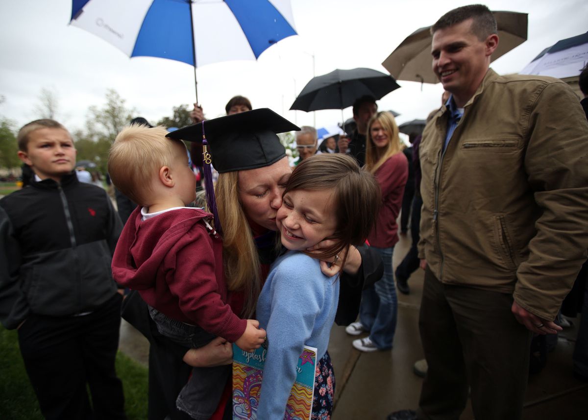 Kim Reeves holds son Gunnar and kisses daughter Brooke as husband Jesse, right, looks on after the S.J. Quinney College of Law commencement ceremony at the University of Utah in Salt Lake City on Friday, May 11, 2018. Kim Reeves' son Austin is on the far 