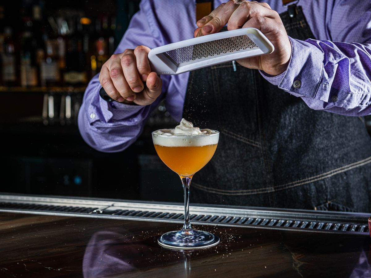 An orange cocktail meticulously made at a bar