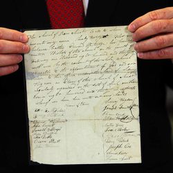 Assistant Church Historian and Recorder Richard E. Turley Jr. of The Church of Jesus Christ of Latter-day Saints displays a historical document bearing the signatures of several early church leaders during a 2013 press conference for the church's ongoing Joseph Smith Papers project.