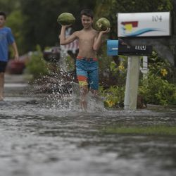 Logan Wilkins from North Carolina plays in the waters on Fort Myers Beach, Fla., Monday, July 31, 2017. Tropical Storm Emily began trekking east across the Florida peninsula on Monday, scattering drenching rains amid expectations it would begin weakening in the coming hours on its approach to the Atlantic coast. (Andrew West/The News-Press via AP)
