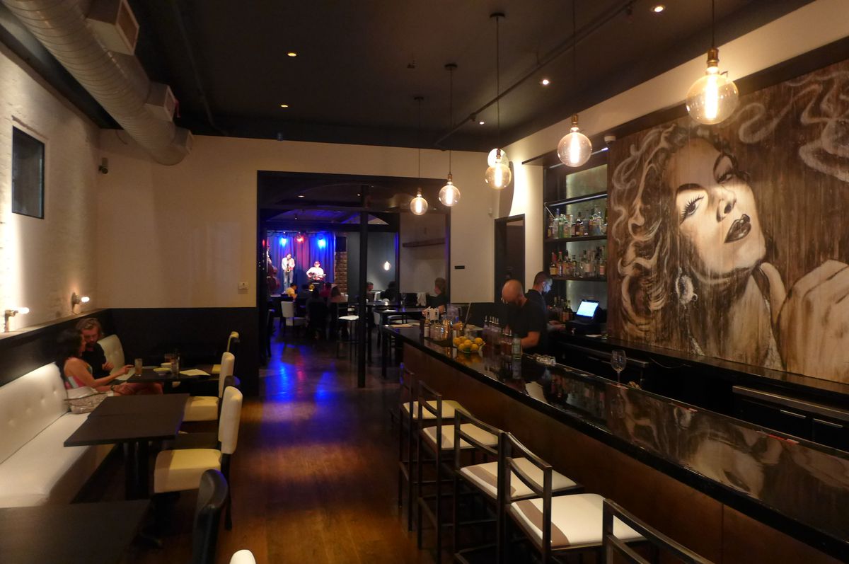 A darkened room with black and white decor and a bar at the right.