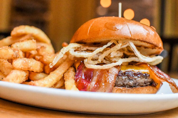A Deluxe burger at Longfellow Grill comes piled high with candied bacon and crispy onion strings.