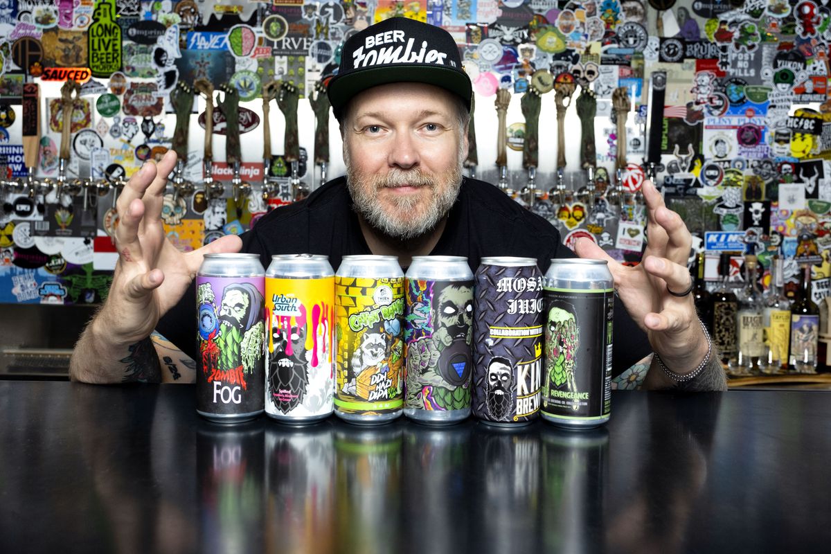 A man holds his hands on either side of six beer cans