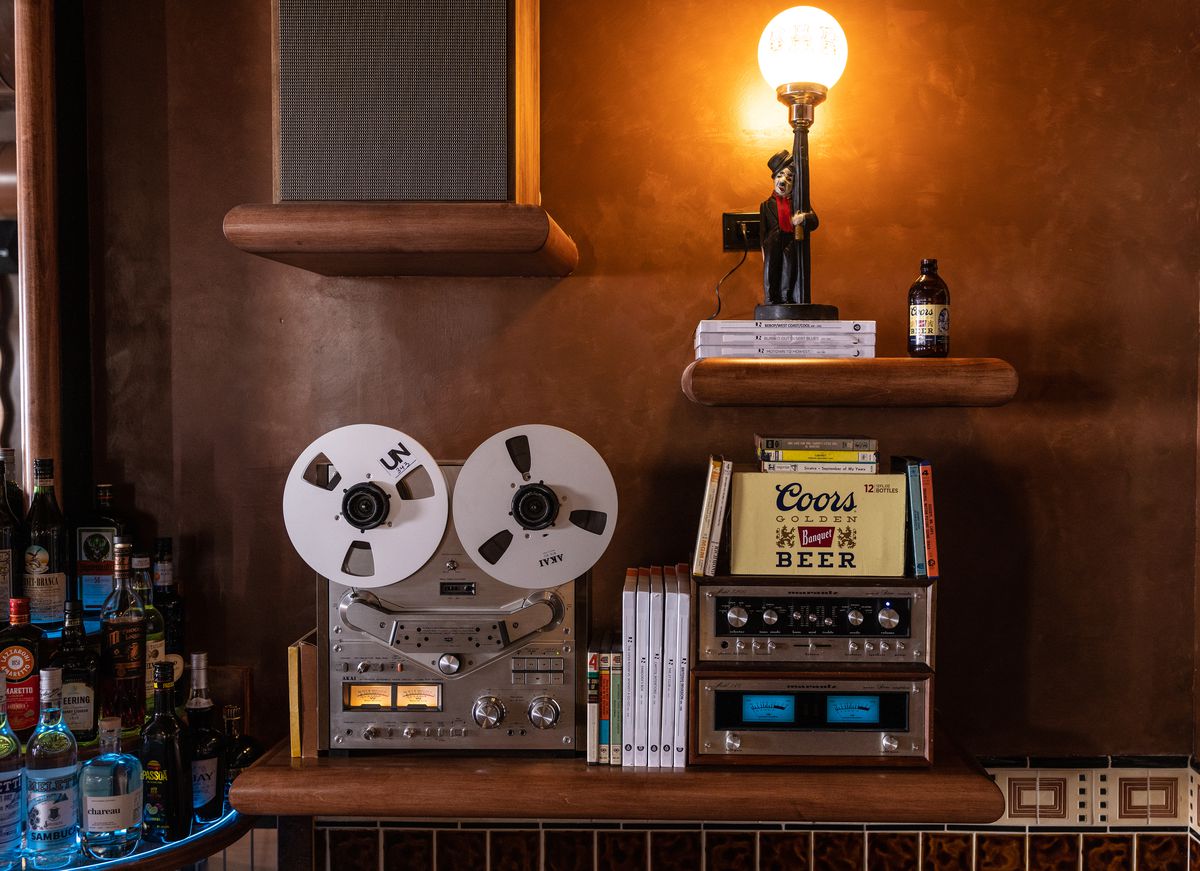 A reel-to-reel machine and old Coors Light box inside of a vintage bar.
