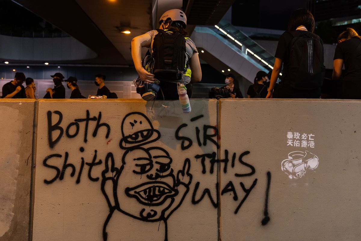 graffiti of Pepe the Frog with protesters behind it in Hong Kong