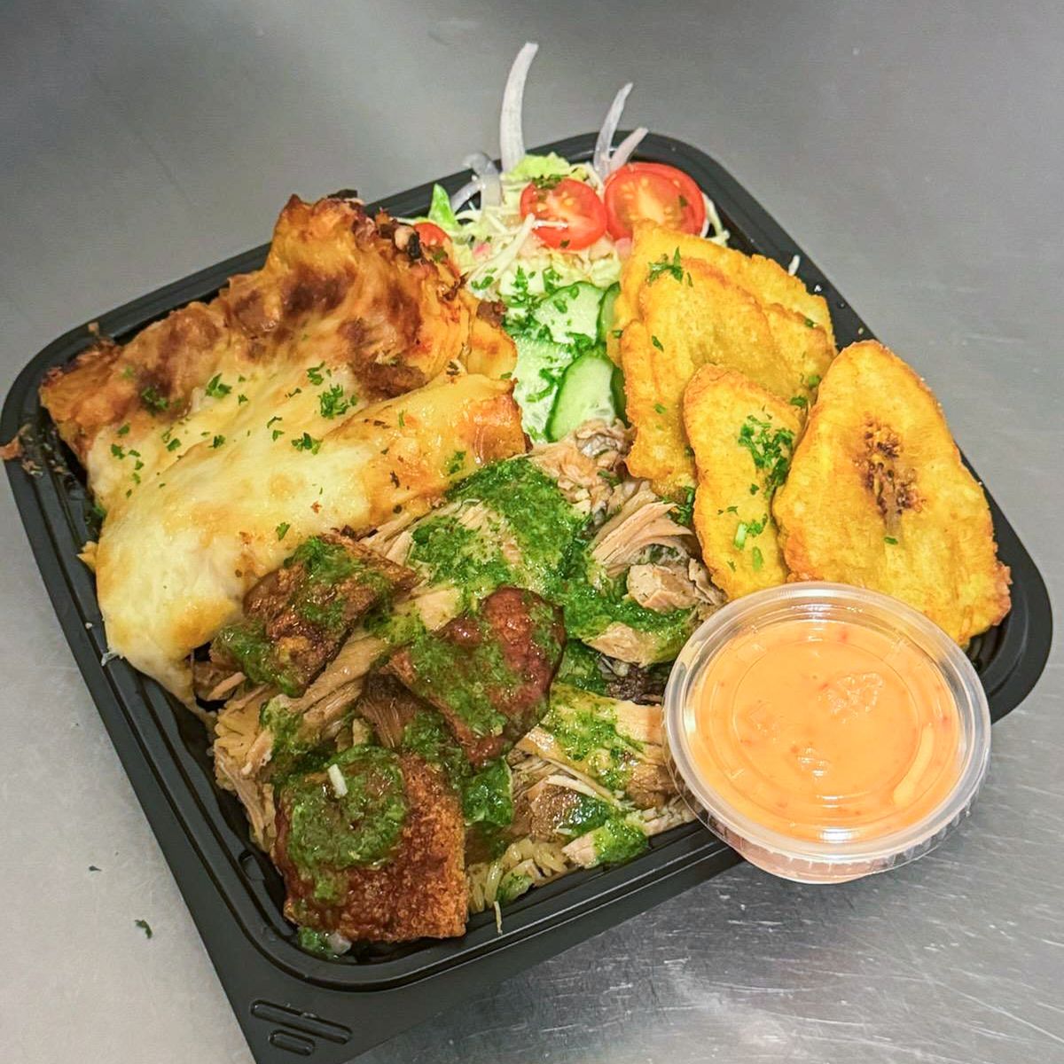 A takeout container of Dominican food with lasagna and fried plantains.
