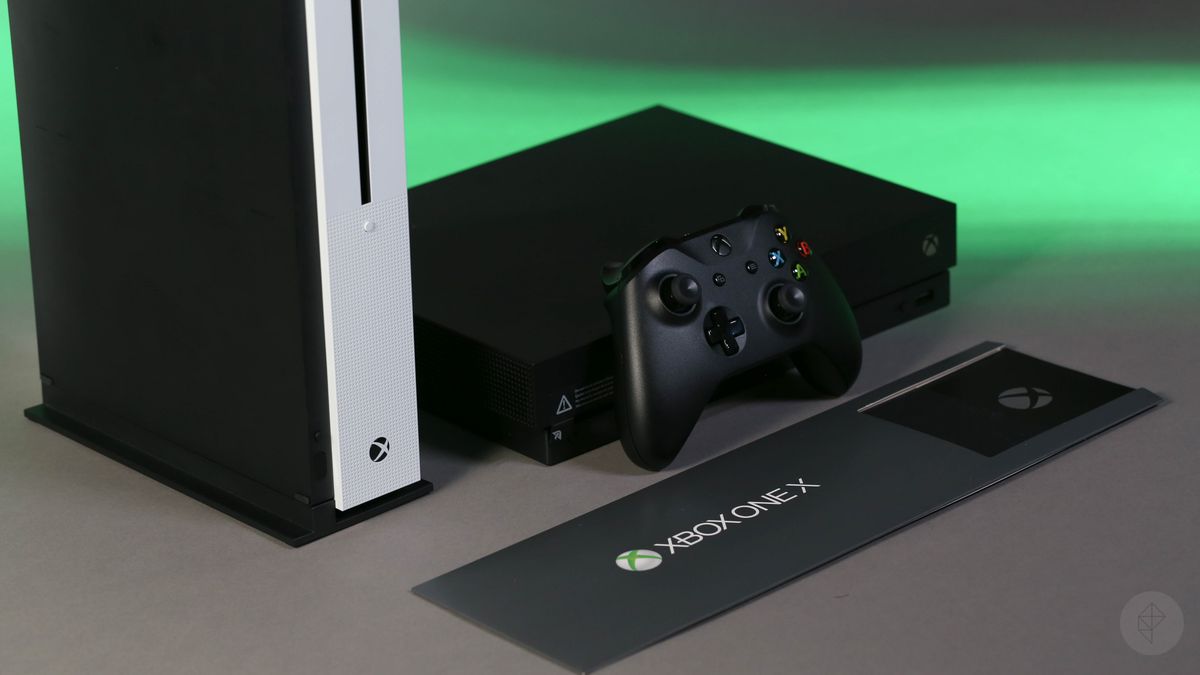 Xbox One X with controller in front and vertical Xbox One S to the left