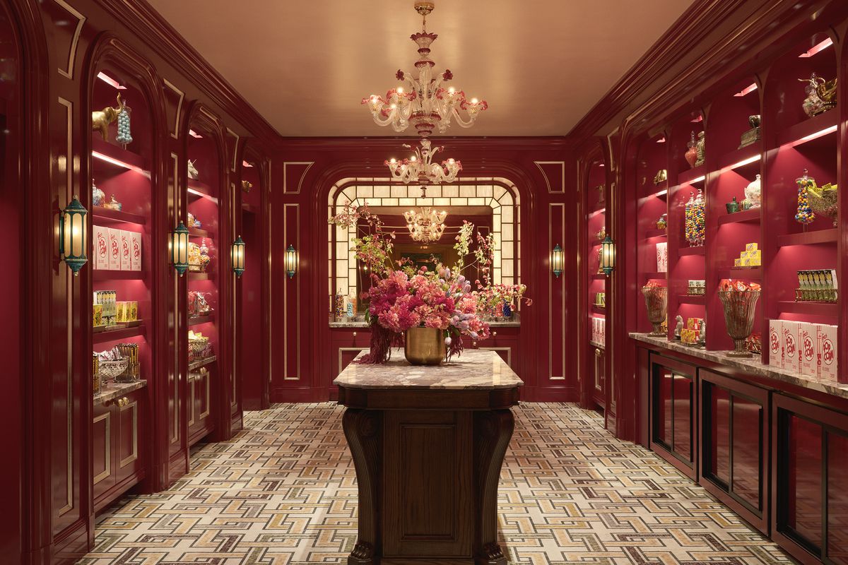 A pantry area with red wood walls and gold finishes. Shelves are stocked with popcorn and other candy and snacks.
