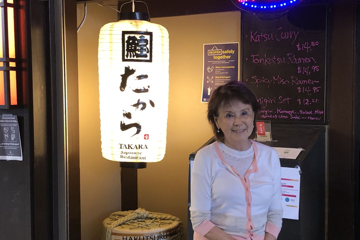 Takara owner Lena Turner stands next to the lantern sign in front of her restaurant Takara