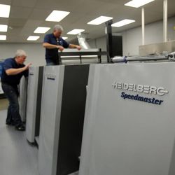 Operators load plates into the Heidelberg Speedmaster XL 106 printing press at KP Corporation in Salt Lake City on Wednesday, June 19, 2013.