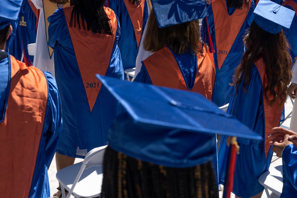 Graduates wearing blue gowns and mortar boards with gold stoles