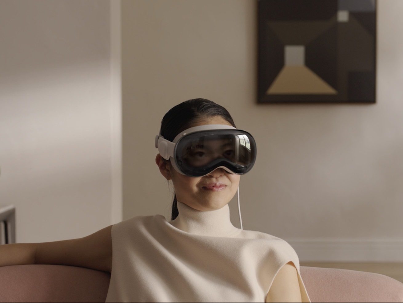 A woman sitting in a living room wearing virtual reality goggles.