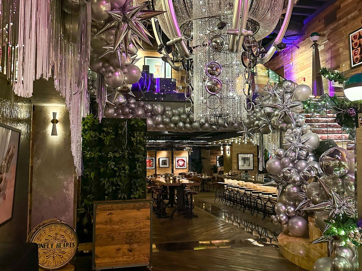 A hotel lobby with a long staircase decorated with silver balloons, purple fabric, and a cascading chandelier