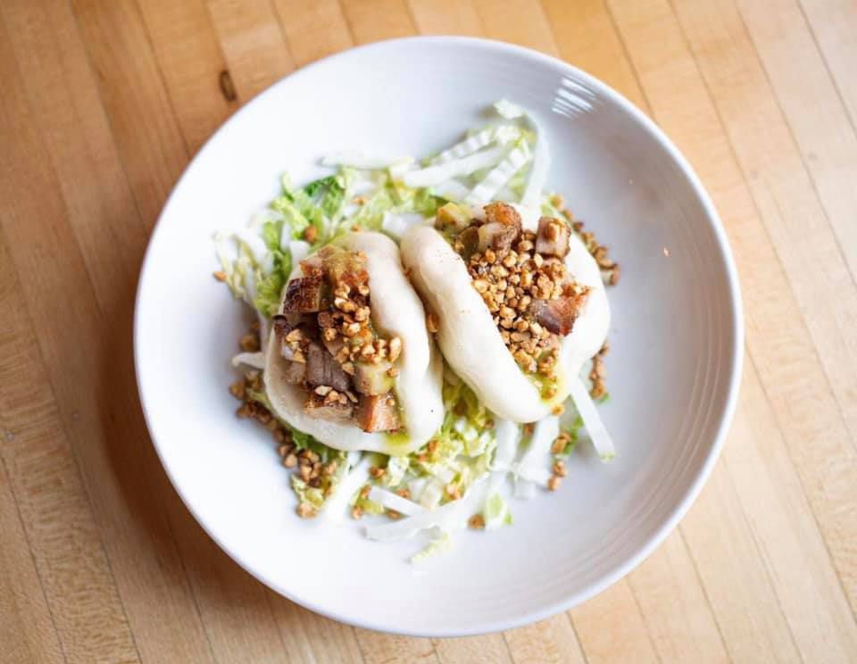 Two back-to-back pork buns on a bed of chopped lettuce with crunchy fixings