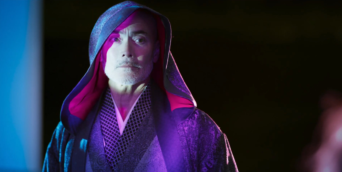 Mark Dacascos wears a hood over his head as purple light bounces off him in Blade of the 47 Ronin.
