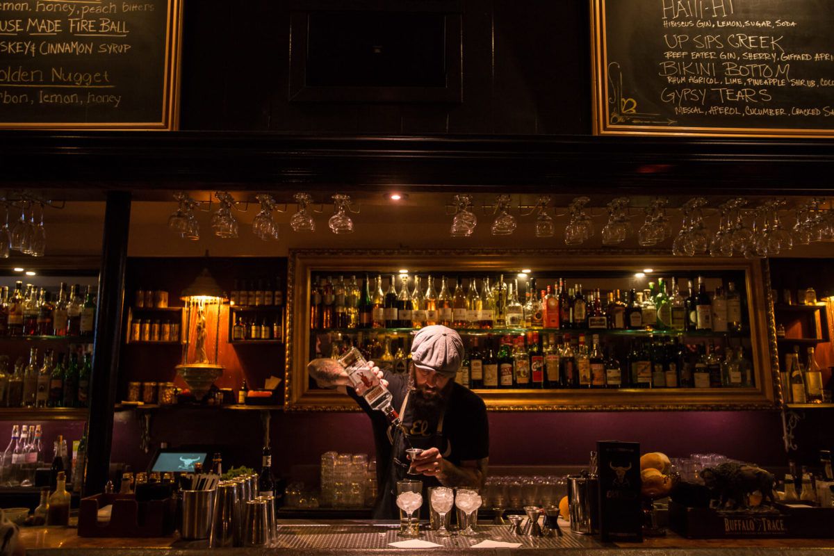 A bartender mixes a drink behind a bar.