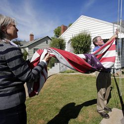 Twins Donald Dunn and Deanna Golden take down the flag at their parents' home Monday, Oct. 7, 2013. Their parents, Jerry and Edith Dunn, were born the same year and died last week within hours of each other.