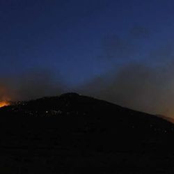 A crescent moon shines over the fire burning near Saratoga Springs Friday, June 22, 2012.