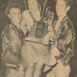 Elwyn Peterson, left, and Jack Hadfield, right, hold up Carol Simpson, the Brigham City Fourth Ward's team sponsor, and the championship trophy. Hadfield said church buildings used to contain trophy cases. 