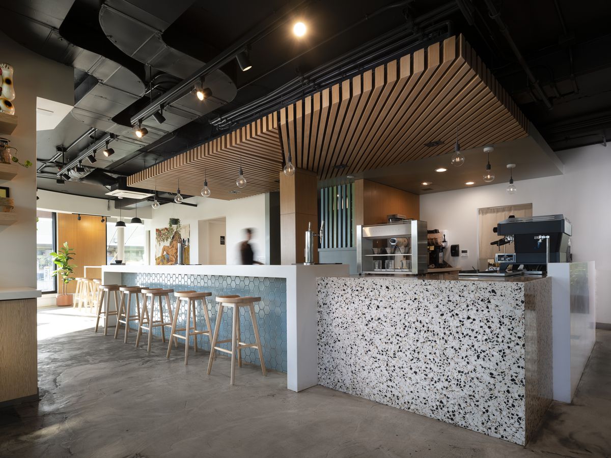 An airy cafe interior with stools at a counter and a prep area. 